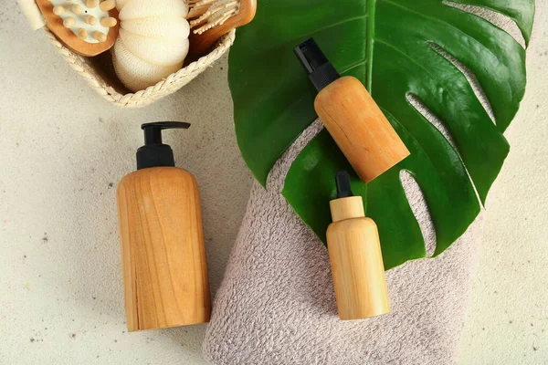 Composition with cosmetic products, bath supplies and palm leaf on light background