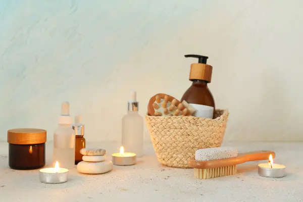 Composition with cosmetic products, spa accessories and burning candles on light background