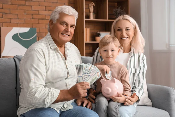 Little boy with his grandparents putting money in piggy bank at home