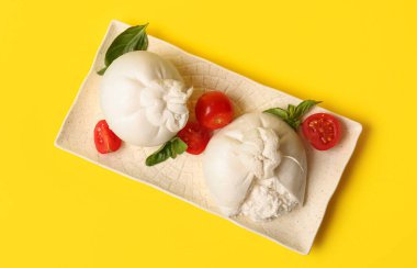 Sarı arka planda lezzetli Burrata peyniri tabağı.