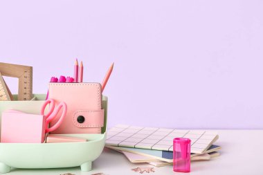 Aydınlık masa üzerinde farklı kırtasiye malzemesi ve defterleri olan tutucu, kapat