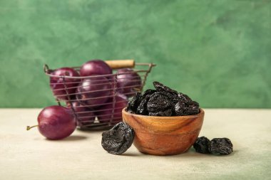 Lezzetli eriklerle dolu bir kase ve yeşil arka planda beyaz grunge masasında olgun erikler.