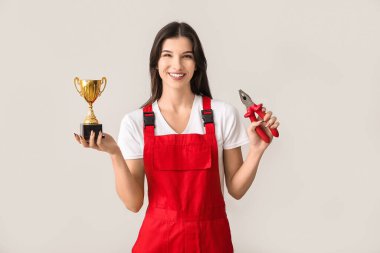 Altın bardaklı ve arka planda kerpeten olan kadın işçi.