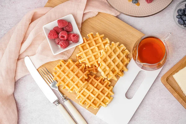 stock image Wooden board of tasty waffles with raspberries and and maple syrup on white background