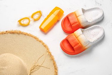 Plaj aksesuarları ve beyaz arka planda güneş kremi olan kadın tarzı terlikler.