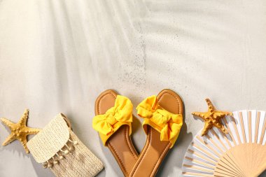 Beyaz arka planda plaj aksesuarları olan şık bayan terlikleri.