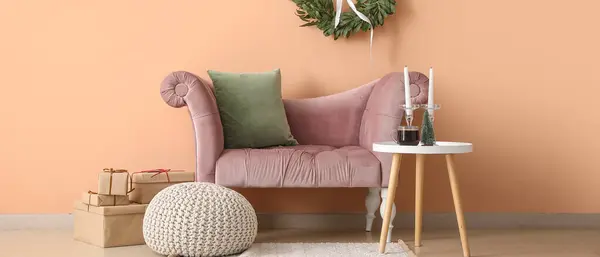 Interior of living room with pink armchair, table and Christmas decorations