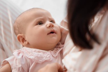 Mutlu bir anne ve küçük tatlı bir bebek yatakta oturuyor.