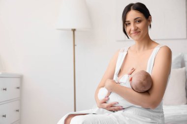 Mutlu anne küçük bebeğini yatak odasında emziriyor.