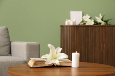 Güzel zambak çiçeği, yanan mum ve kitap odasındaki ahşap masada.