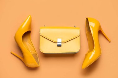 Sarı topuklu ayakkabılar ve kahverengi arka planda çanta.