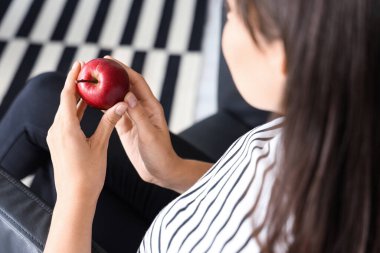 Evdeki oturma odasında taze elmalı güzel bir kadın.