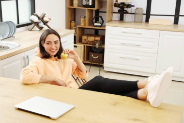 Mutfaktaki masada taze elmalı güzel bir kadın oturuyor.