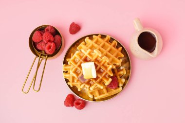 Pembe arka planda ahududu ve akçaağaç pekmezli lezzetli waffle tabağı.