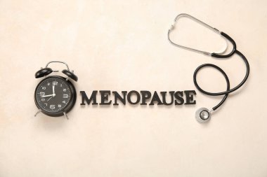 Alarm saati ve steteskoplu sözcük MENOPAUSE hafif arkaplanda