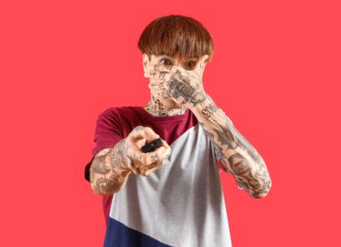 Kırmızı arka planda dövmeli, korkmuş genç bir adam.