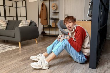 Korkmuş, dövmeli bir adam evde yerde oturuyor.