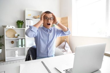 Ofiste oturan dizüstü bilgisayarlı genç bir işadamı.