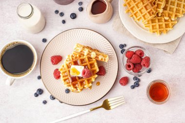 Böğürtlenli waffle, akçaağaç şurubu, beyaz arka planda süt ve kahve.