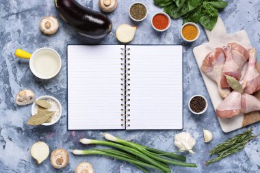 Boş tarif kitabıyla kompozisyon, taze baharatlar ve arka planda tavuk bacağı