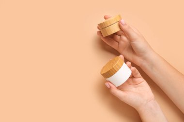 Renkli arka planda kozmetik ürünlerin kavanozları olan kadın elleri