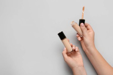 Hafif arka planda sıvı makyaj fonuna sahip kadın elleri.