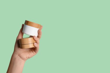 Renkli arka planda kozmetik ürünlerin kavanozlarıyla kadın eli, yakın plan