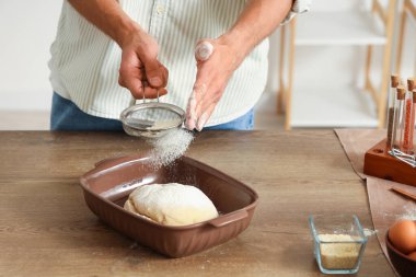 Fırındaki masaya un serpiştiren yakışıklı genç adam.