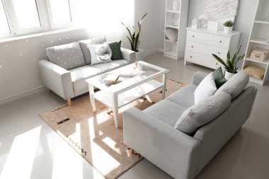 Modern oturma odasının içinde gri kanepeler, asılı disko topu ve kahve masası.