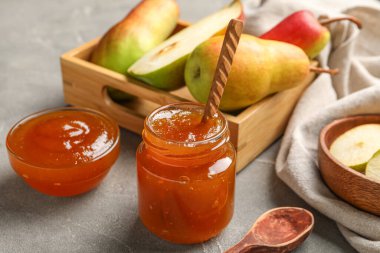 Cam kavanoz ve armut reçeli. Gri masa üzerinde ahşap kutu.