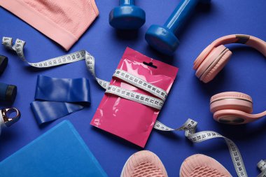 Mavi arka planda atıştırmalık, spor malzemeleri ve kulaklıklı kompozisyon