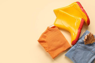 Renkli süveter, kot pantolon ve sonbahar yapraklı sarı çizmeler