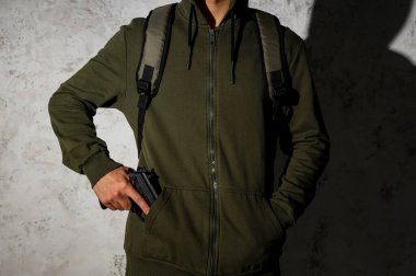 Ceplerinde silah olan bir erkek öğrenci, grunge wall 'ın yanında, yakın plan.