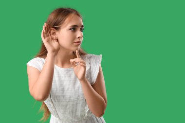 Teenage girl trying to hear something on green background clipart