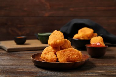 Lezzetli nugget tabağı ve ahşap arka planda bir kase ketçap.