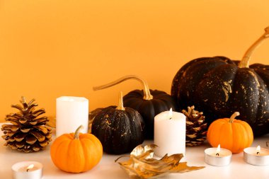 Sarı duvarın yanında balkabakları ve mumlar