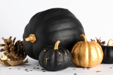 Beyaz arka planda altın renkli balkabakları ve yaprağı var.