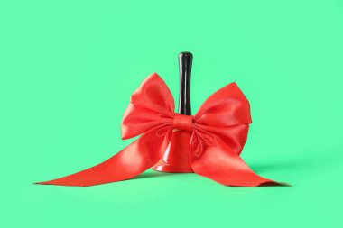 Yeşil arka planda kırmızı kurdeleli Noel çanı