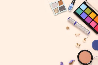 Farklı makyaj ürünleri ve açık arkaplanda güzel çiçekler olan kompozisyon