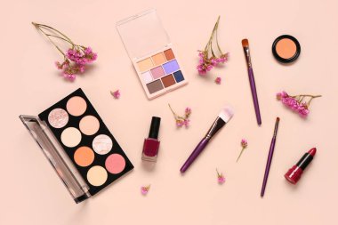 Farklı makyaj ürünleri ve pembe arka planda güzel çiçekler olan kompozisyon