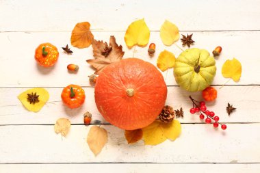 Olgun balkabaklarıyla, böğürtlenlerle, baharatlarla ve açık ahşap arka planda düşmüş yapraklarla sonbahar kompozisyonu