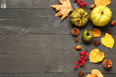 Olgun balkabakları, böğürtlenler, baharatlar ve koyu ahşap arka planda düşmüş yapraklarla sonbahar kompozisyonu