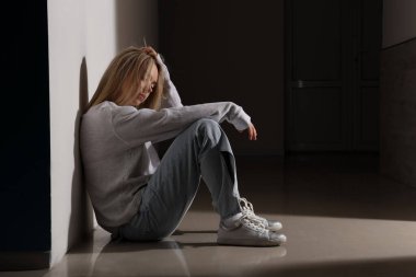 Depresyondaki genç kadın koridorda oturuyor.