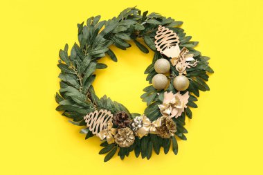 Sarı arka planda güzel süslemeleri olan Noel ökseotu çelengi