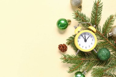 Noel kompozisyonu alarm saati, köknar ağacı dalları ve sarı arka planda mücevherler