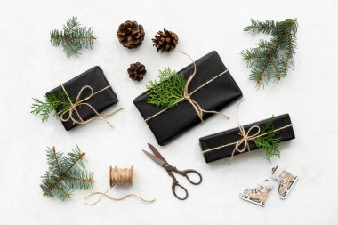 Beyaz arka planda Noel ağacı dalları ve konileri olan siyah hediye kutuları