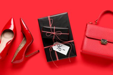 Yüksek topuklu ayakkabılar, el çantası ve kırmızı arka planda hediye kutuları. Kara Cuma indirimi