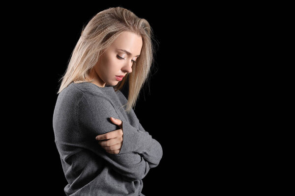 Depressed young woman on dark background
