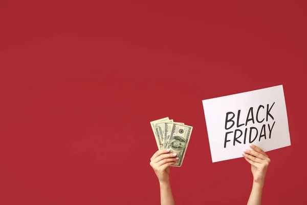 Female hands holding poster with text BLACK FRIDAY and money on red background