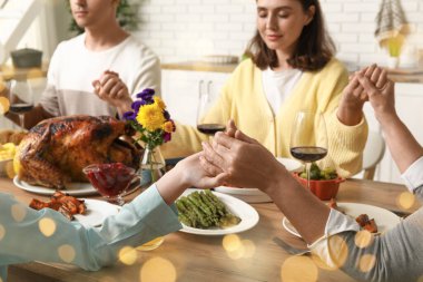 Şükran Günü 'nde yemekten önce dua eden mutlu bir aile.